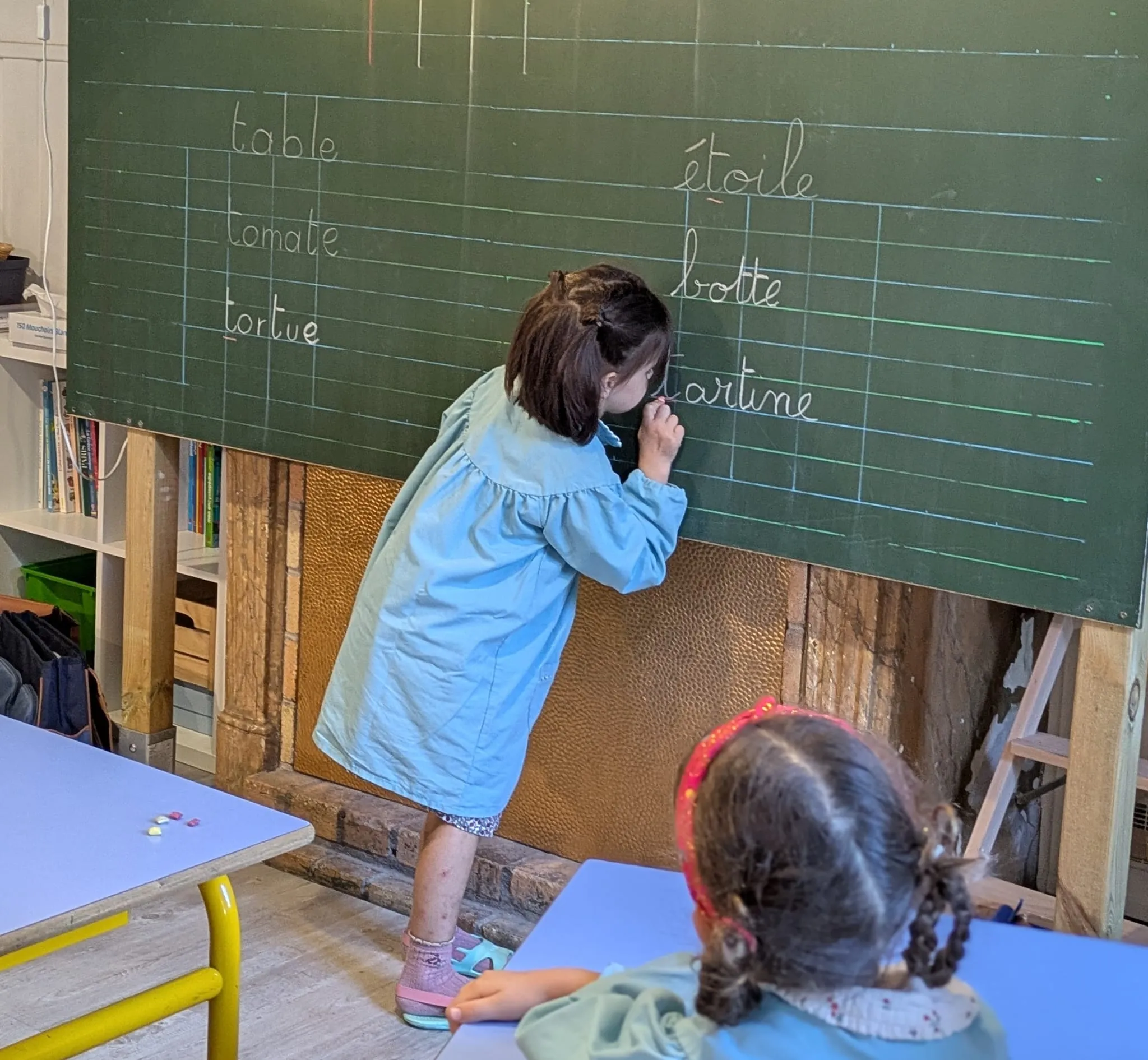 Une élève écrit au tableau les mots de la leçon