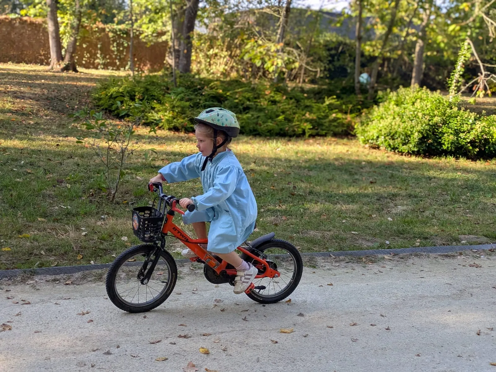 Une petite élève de maternelle à vélo dans l'allée du parc
